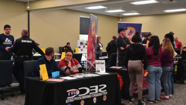 Students visit with a uniformed man at an event for Criminal Justice career exploration.